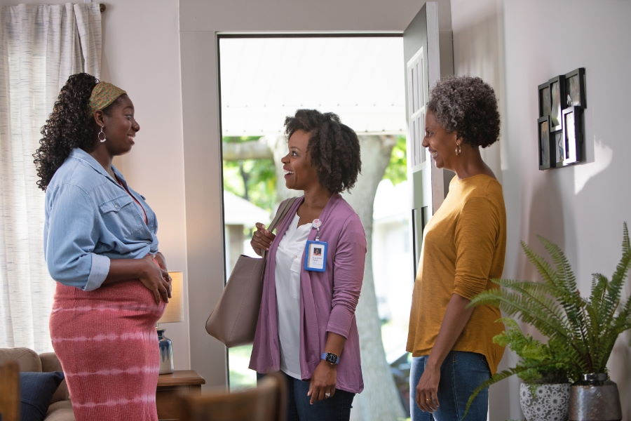 A pregnant woman and her mother greeting a family support provider at the door